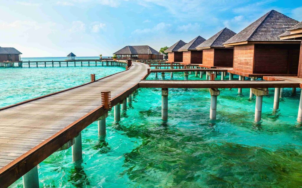 a long walkway leading to a row of huts on stilts over water