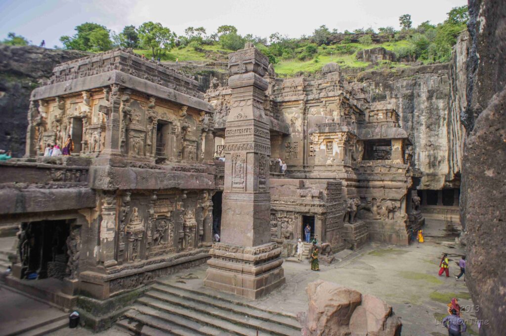 a stone building with carved carvings with Ellora Caves in the background