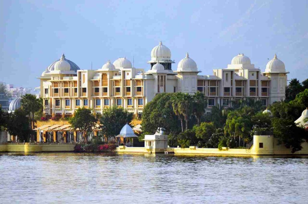 a building with domes and trees next to a body of water