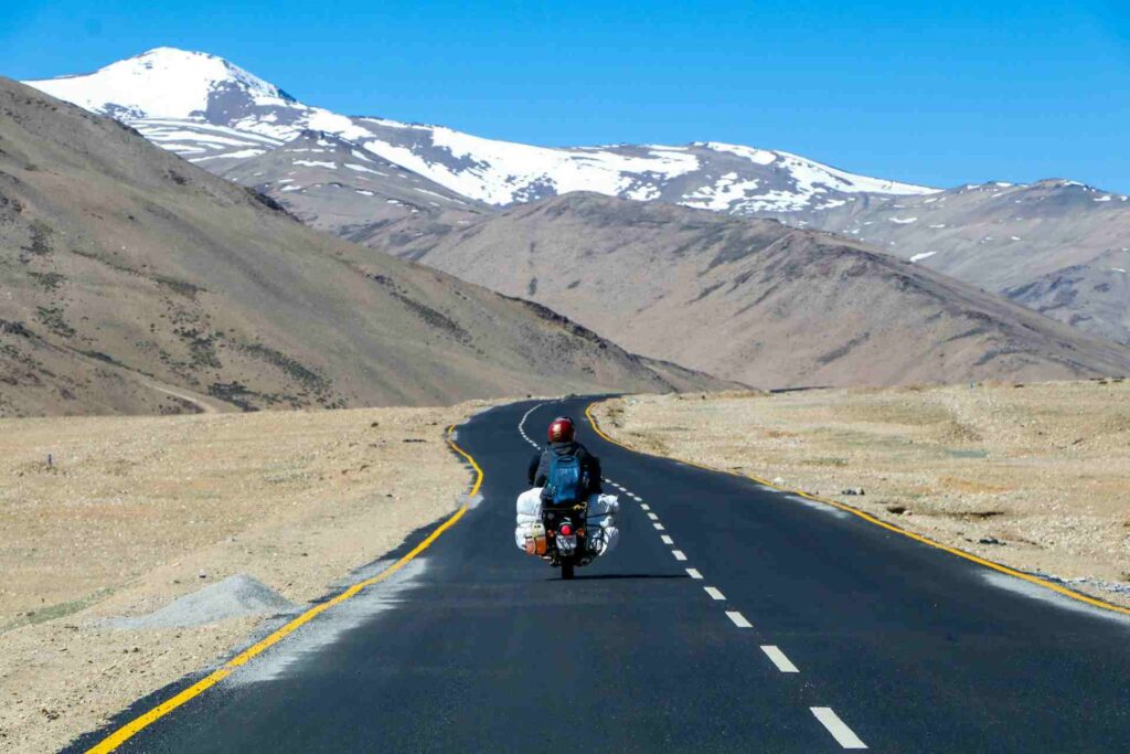  A person riding a motorcycle on a road with mountains in the background