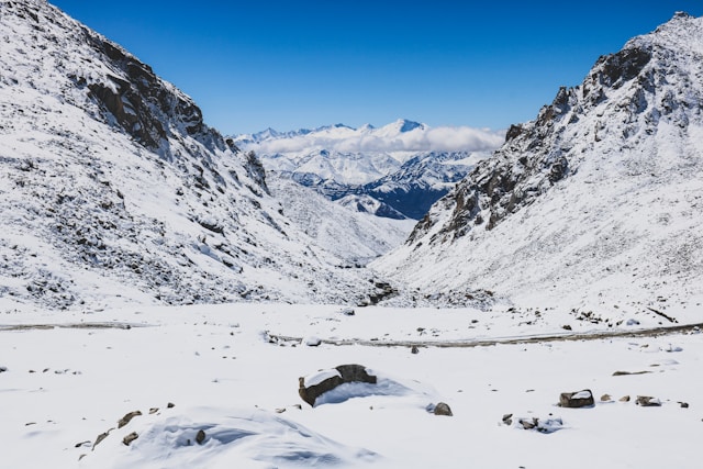 A scenic snowy mountain valley with a road winding through it, offering a picturesque winter landscape.