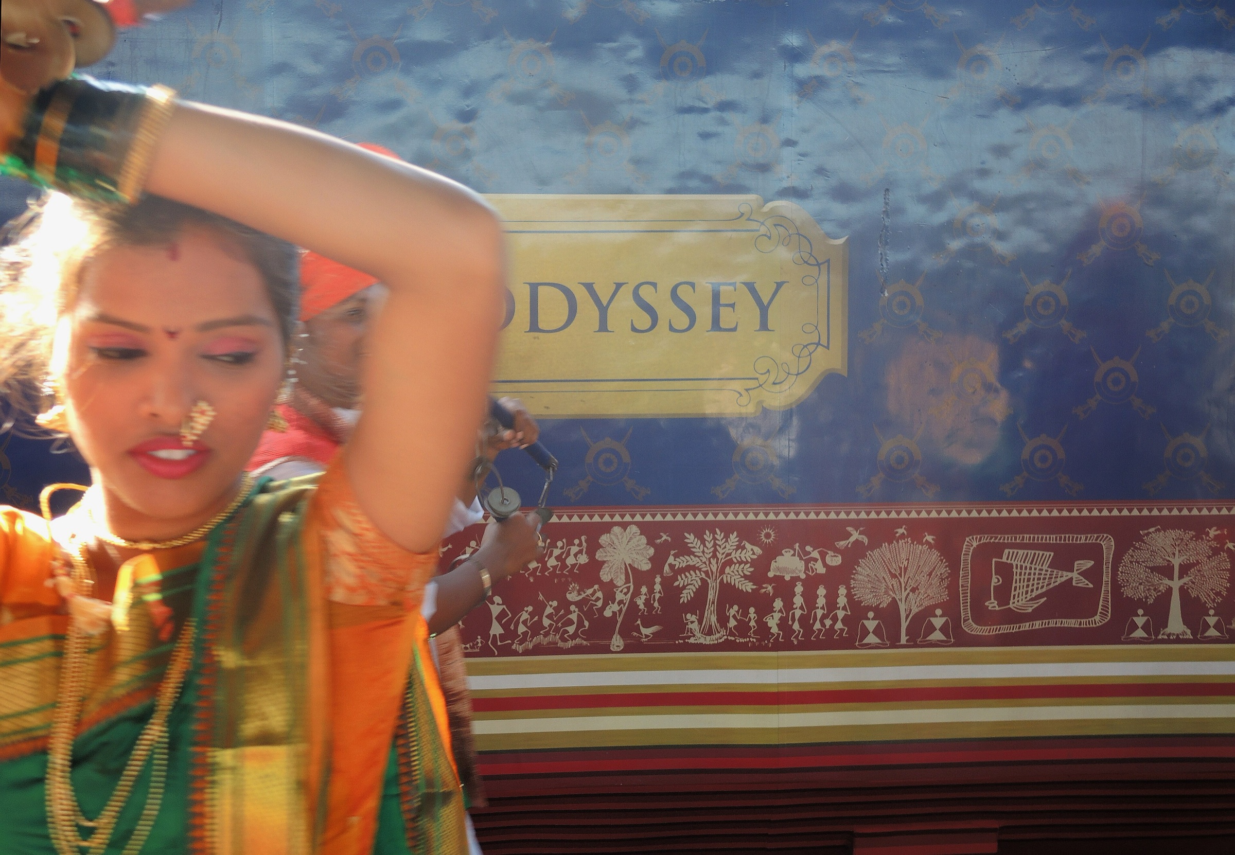 A Maharashtrian dancer at the Deccan Odyssey welcome, beside the train's Warli-art livery